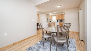 A modern kitchen with wooden cabinets, a central island, and a dining area with a round table and chairs.