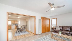 A spacious living area with a dining table, a brown leather sofa, and a ceiling fan.