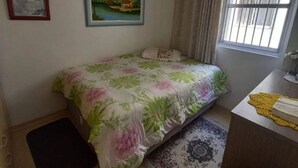 Una camera da letto con un letto, una scrivania, una finestra, una ventola a soffitto e due quadri appesi al muro.