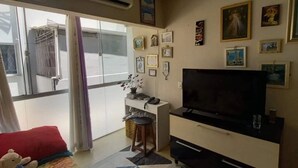 Una camera d'albergo con un letto, una scrivania con computer, una TV e una finestra con tende.