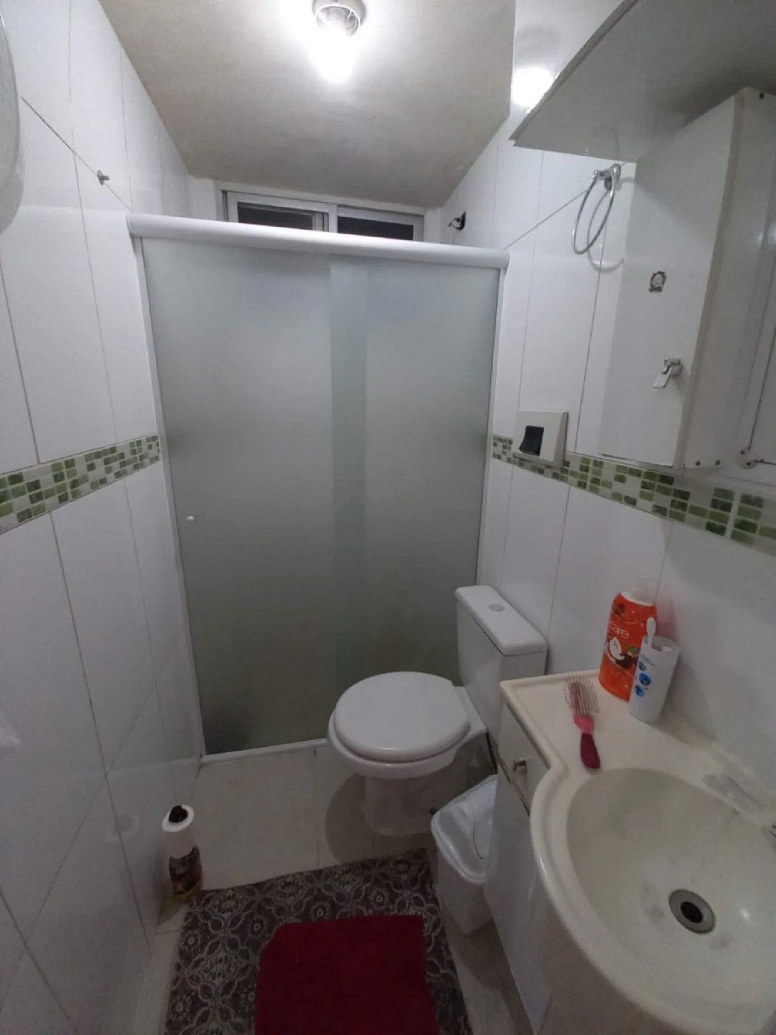 A small bathroom with a toilet, sink, and shower.