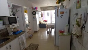 Una cucina compatta con forno a microonde, frigorifero e zona pranzo con tavolo e sedie.