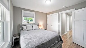 Une chambre à coucher avec un lit, des tables de chevet, une fenêtre et une porte.