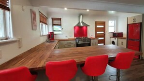 Una cucina con isola in legno, sedie rosse, un frigorifero rosso e una lavatrice.