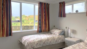 Una camera da letto con due letti, un comodino e una finestra con tende.