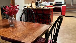 A modern kitchen with red cabinets, a wooden dining table, and black chairs. - Peaceful Farmhouse & Rural Views (Sabina)