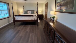 A bedroom with a four-poster bed, a ceiling fan, two bedside lamps, a dresser, and a large framed picture on the wall. - Peaceful Farmhouse & Rural Views (Sabina)
