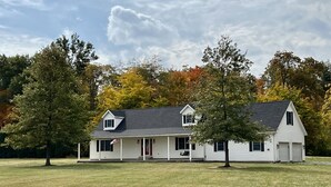 A single-story house with a front porch, a garage, and a flagpole with an American flag. - Peaceful Farmhouse & Rural Views (Sabina)
