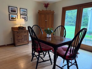 A dining area with a wooden table, black chairs, a lamp, and framed pictures on the wall. - Peaceful Farmhouse & Rural Views (Sabina)