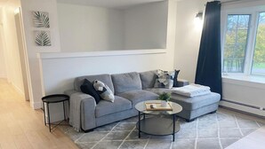 Ein modernes Wohnzimmer mit einem grauen Sofa, einem runden Couchtisch und einem kleinen Beistelltisch.
