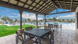 Un patio al aire libre con piscina, sillones de descanso y un área de estar cubierta.