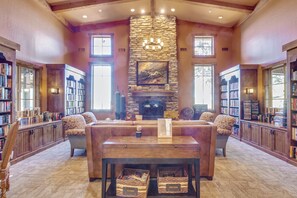 A spacious library with a stone fireplace, leather seating, and tall bookshelves. - 2 King Beds! Private Spa! 2 Bedroom & 2 Bathroom Home in Queen Creek! (Queen Creek)