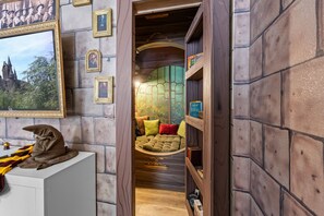 Una habitación acogedora con pared de piedra, un cuadro enmarcado, una estantería y una cama con almohadas.