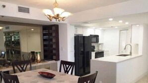 Eine moderne Küche mit Einbaukühlschrank, Mikrowelle und Spüle. Ein Essbereich mit Tisch und Stühlen ist vorhanden.