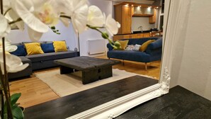 A living room with a sofa, armchair, coffee table, and a mirror reflecting the space. - Stunning Luxury 2 Bed City Centre Apartment (Derby)