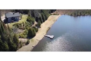 Overlooking a serene lake, this property offers a tranquil retreat with a dock and a spacious house surrounded by lush trees.
