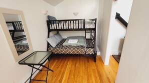 A small, compact room with a bunk bed, a small table, and a mirror. - Bear Lake Cottage near Kingston (Arden)