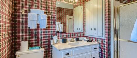 Un baño con papel tapiz estampado en cuadros, un lavabo blanco y un espejo encima.