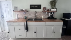 Una cocina con un lavamanos empotrado, una cafetera y una planta en maceta.