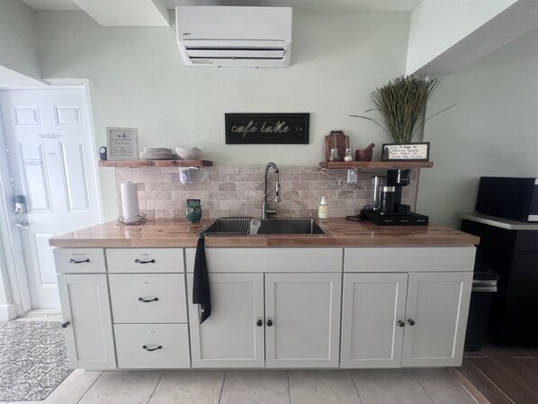 Una cocina con un lavamanos empotrado, una cafetera y una planta en maceta.