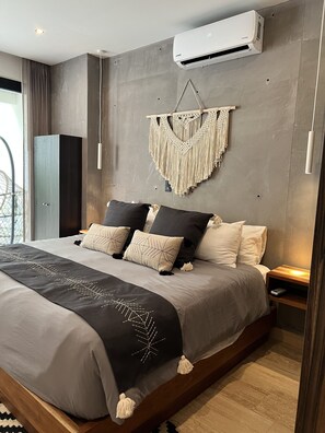 A modern bedroom with a large bed, a macrame wall hanging, and an air conditioning unit. - Jungle's Prince. A Boho-chic Condo.
Spacious, Confortable and Luxury (Tulum)