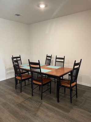 A dining area with a rectangular wooden table surrounded by six black chairs with wooden seats.