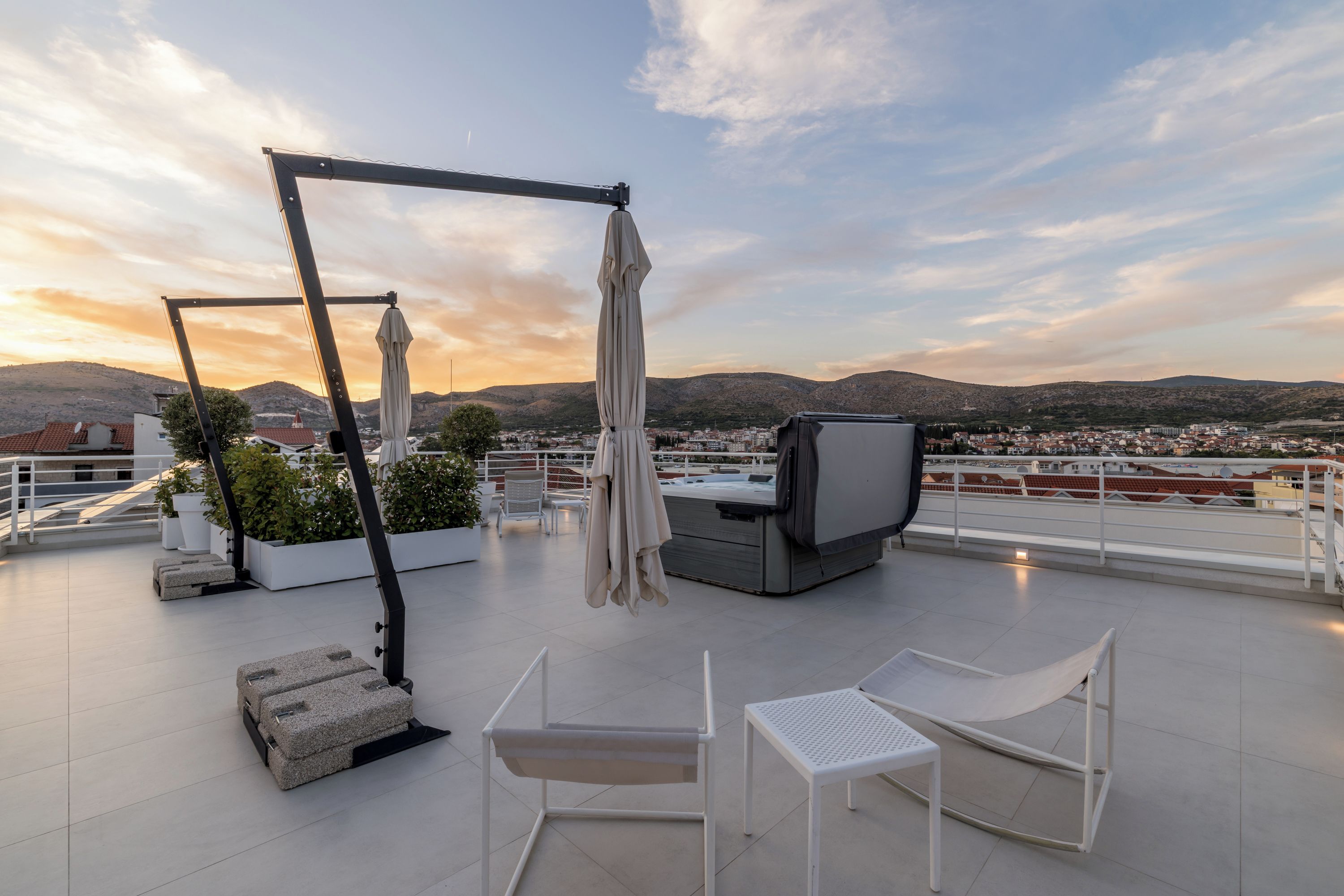 A rooftop terrace with a hot tub, lounge chairs, and a pergola with a canopy.