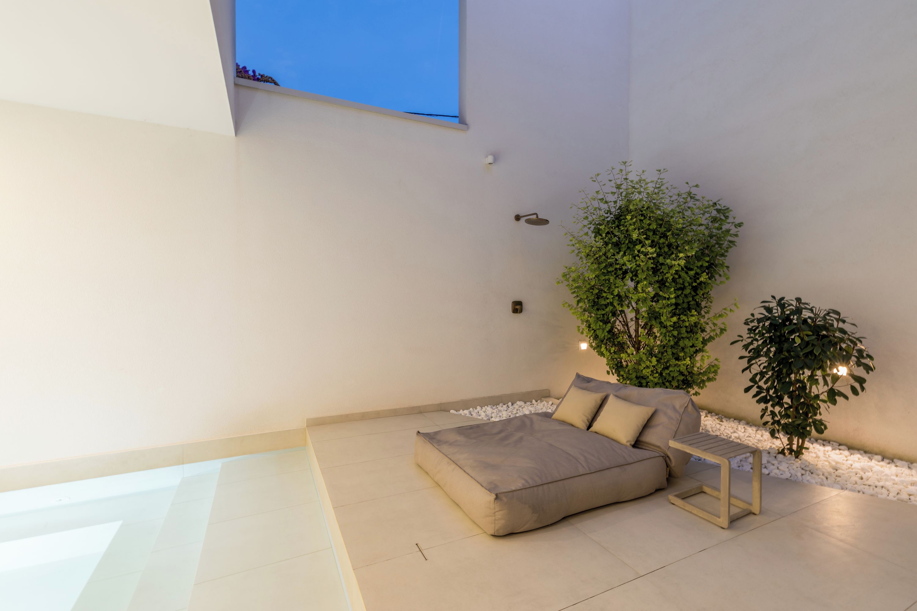 A modern bedroom with a bed, a small table, and a potted plant.
