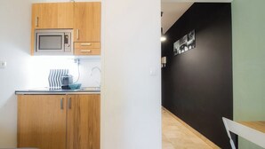 A kitchen with wooden cabinets, a microwave, and a sink. - Reve de Jade devant le canal (Annecy)