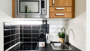 A kitchen with a microwave, kettle, and sink. - Reve de Jade devant le canal (Annecy)