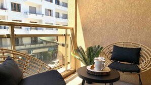 A balcony with wicker chairs, a small round table with a coffee cup, and a potted plant. - Reve de Jade devant le canal (Annecy)