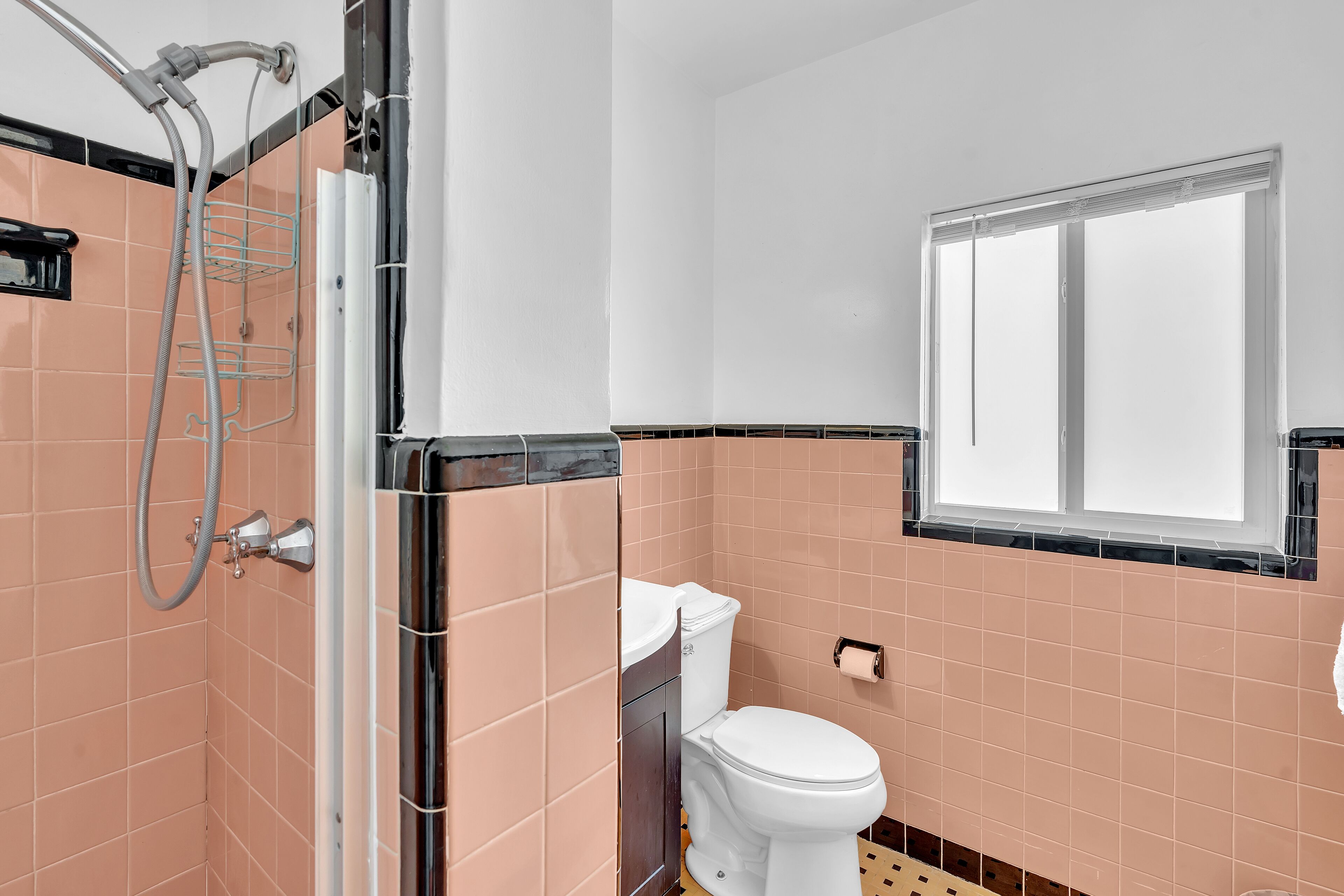 A bathroom with a shower, toilet, and a window.