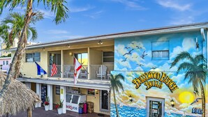 Edifício com um mural de hotéis de Hollywood Beach, uma varanda e uma bandeira.