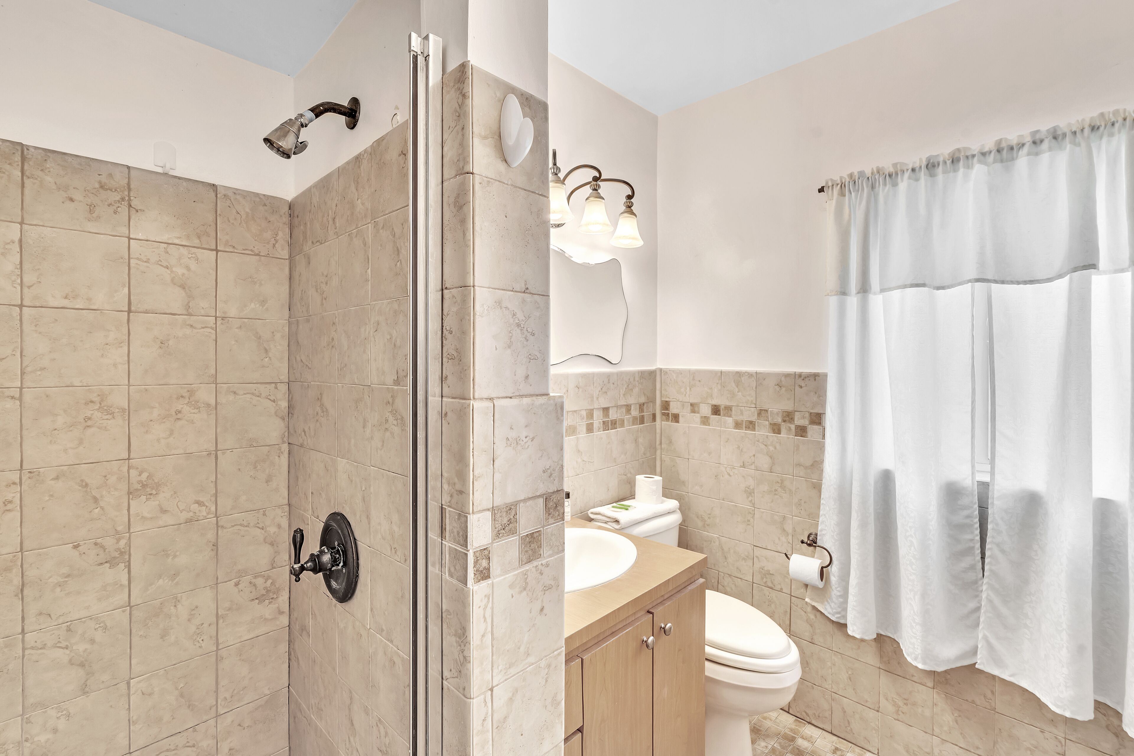 Une salle de bain équipée d’une douche, de toilettes, d’un lavabo et d’un meuble-lavabo.