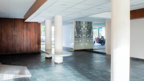 A spacious lobby with a dark tiled floor, a central white column, and a large decorative panel with a swan motif. - Biloba du Lac (Annecy)