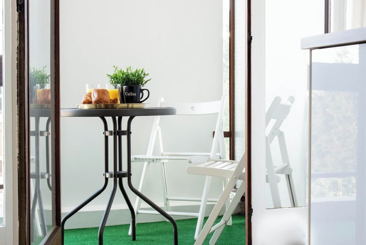 Un balcon avec une table, des chaises, une tasse à café et une plante.