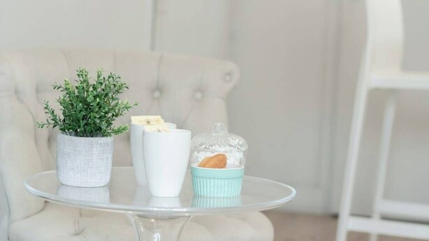 A small round glass table with a potted plant, a white vase, and a blue container with cookies. - Lafayette 2 vélos proche du lac (Annecy)