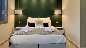 A modern bedroom with a large bed, two bedside tables, and a green accent wall.