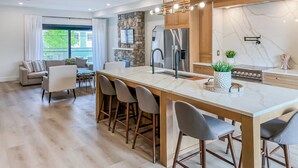 A modern kitchen with a marble countertop, stainless steel appliances, and a stone accent wall. - Luxury townhome - Rooftop Patio - Hot Tub (Charlottetown)