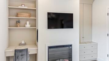 A modern room with a built-in TV, a fireplace, and a desk with a chair.