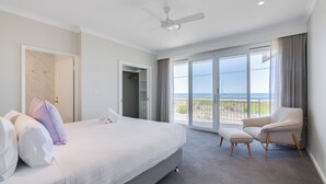 Ein modernes Hotelzimmer mit einem großen Bett, einem Sessel und einem Balkon mit Meerblick.