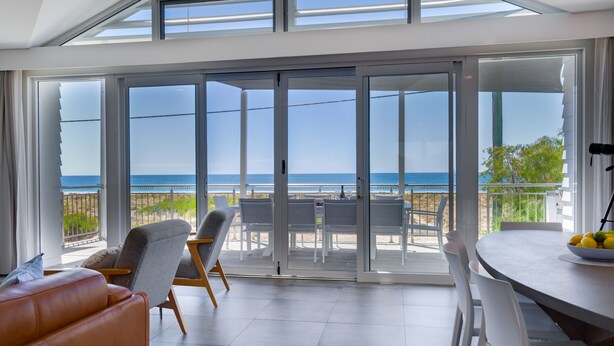 Ein modernes Zimmer mit einer großen Schiebeglasdoor, die zu einem Balkon mit Meerblick führt.