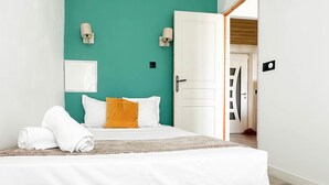 A neatly made bed with white linens, a single orange pillow, and a white towel on the side. - Etoile des neiges 2 min du centre (Annecy)
