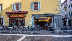 Un café con mesas al aire libre, un edificio amarillo y un letrero que dice "Barbette du Marche".
