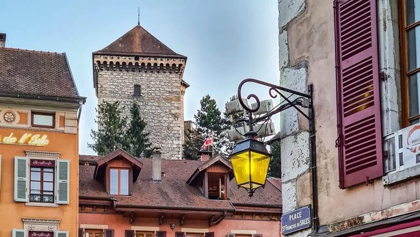 Escena callejera con un restaurante llamado 'LA BASTILLE' que ofrece pizza y especialidades.
