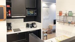 Une cuisine moderne avec des meubles de couleur noire, un four à micro-ondes, une machine à café et un petit coin repas comprenant une chaise et une table.