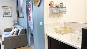 Un salon avec un canapé gris, un ventilateur et un tableau encadré accroché au mur.