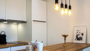 A modern kitchen with white cabinets, a wooden countertop, and a pendant light fixture. - Tahiti Beach 100 m du lac (Annecy)