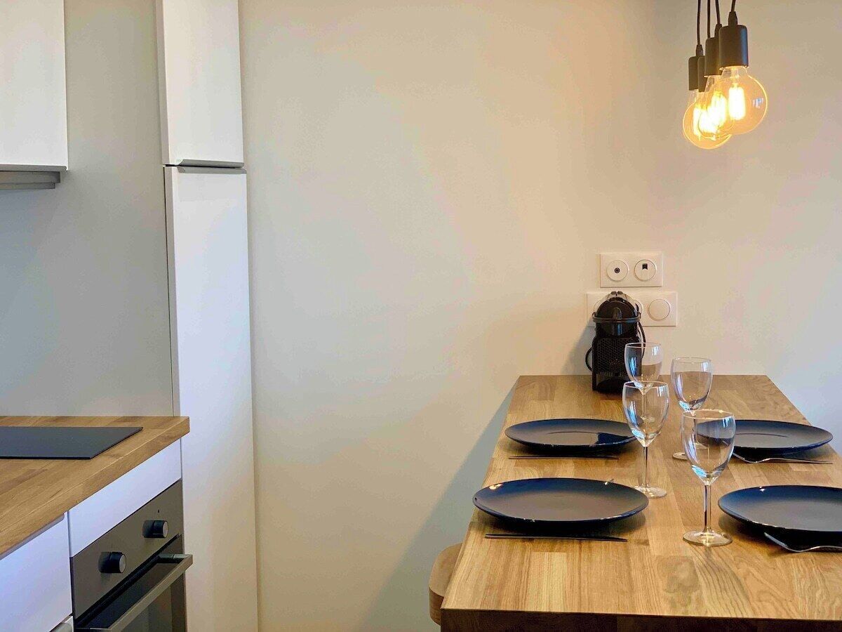 A dining area with a wooden table set for four, including plates and wine glasses.