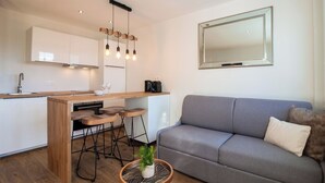A modern kitchen with a central island, bar stools, and a hanging light fixture. - Tahiti Beach 100 m du lac (Annecy)